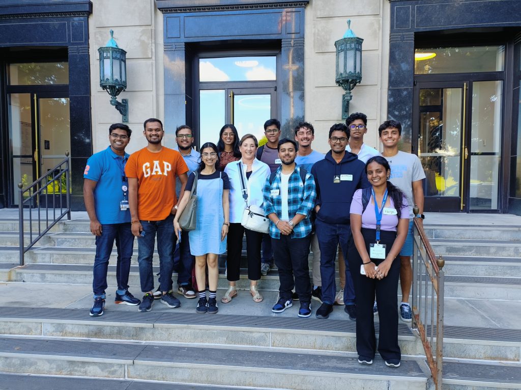 Students pose on steps of Johns Hopkins University building.