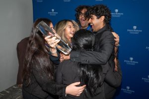 Students in team IRIS embracing and holding a trophy 